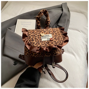Detail of leopard print backpack featuring brown ruffle trim and decorative badges