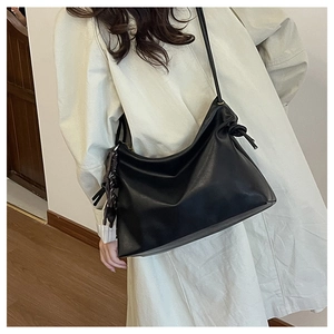 Detail showing knotted shoulder strap on a black oversized leather bucket bag for women