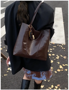 Detailed texture of dark brown polished leather tote bag with vintage beaded charm