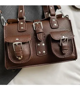 Detail view of dark brown lychee texture leather handbag with silver rivets and buckles