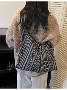Ethnic knit tote bag with black and white geometric patterns shown on a shoulder
