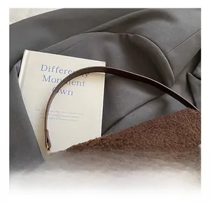 Detail of dark brown faux fur saddle bag with leather piping and gold metal clasp