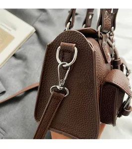 Detail shot of the brown litchi pattern leather bag with silver metal buckle and strap