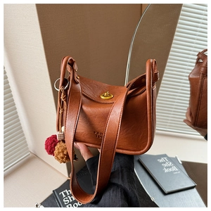 Detail view of brown PU leather bag with twist lock, dual straps, and decorative pompom