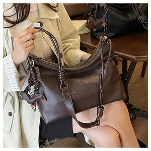 Detail of coffee brown tote bag with thick knot strap and dachshund leather charm