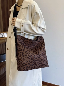 Trendy leopard print large tote bag with eyelet strap worn with a beige trench coat