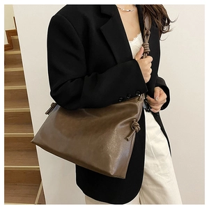 Detail of dark brown leather bucket bag with unique knotted strap and spacious interior