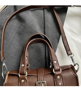 Detail of soft brown pebble leather handbag with durable dual handles and silver hardware