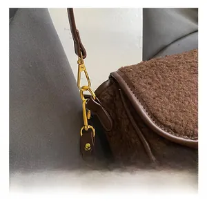 Detail view of the brown plush saddle bag with golden metal hooks and leather strap
