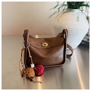 Close-up of brown vintage leather pillow bag with gold clasp and plush charm detail