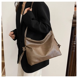Detail of soft brown leather bucket bag showing knot decorative and shoulder strap design