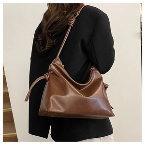 Deep brown leather bucket bag side detail with unique knot and slim shoulder strap