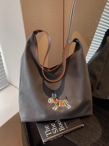 Grey canvas tote bag with zebra embroidery and brown leather straps for commuting