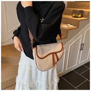 Detail of faux shearling saddle bag with brown leather trim and golden hardware