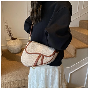 Detail of cream fleece saddle bag with brown leather trim and metal ring hardware
