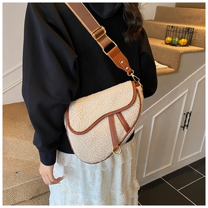 Close-up of saddle bag with cream faux shearling texture and brown leather trim
