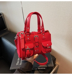 Detail of red lychee grain leather handbag with silver rivets and metal buckles