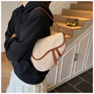 Close-up of saddle bag with beige shearling fabric and brown leather piping detail