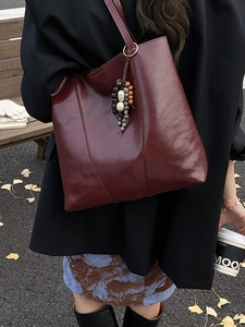 Large burgundy leather tote bag with ethnic bead charm for autumn commuter style