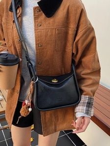 Classic black leather pillow bag with gold clasp and plush charm on a model's shoulder