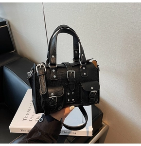 Close-up of black lychee leather handbag featuring silver punk rivets and adjustable strap