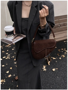 Detail of brown teddy plush saddle bag with leather trim and gold D-shaped hardware buckle