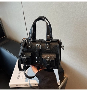 Detailed shot of black lychee-textured leather bag with silver rivets and buckled pockets