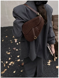 Close-up of brown plush faux fur saddle bag with leather strap and gold hardware