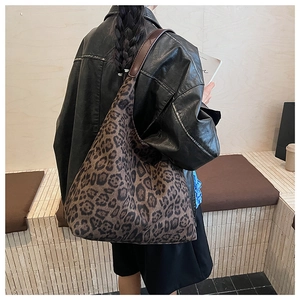 Detail of leopard print tote bag with premium brown leather straps on shoulder