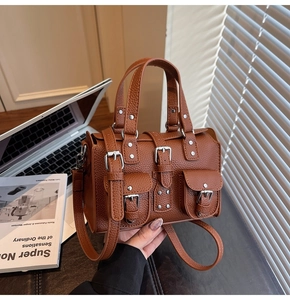 Detail of brown lychee grain leather handbag with vintage metal buckles and shoulder strap