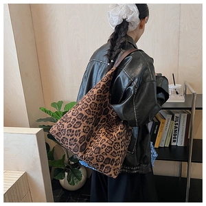 Detailed view of large leopard print tote bag with leather strap on model shoulder