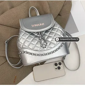 Quilted silver backpack with pink embroidery next to an iPhone 12 for size comparison