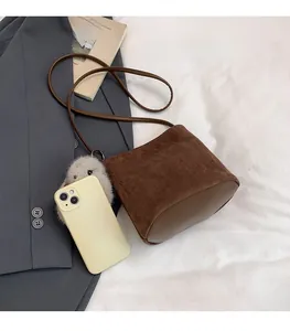 Dettaglio della mini borsa a secchiello marrone con confronto dimensioni con cellulare