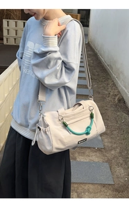 Detail der cremeweißen Nylon-Tragetasche mit grüner Kordel und verstellbarer Schnalle