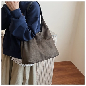 Detail view of large dark grey suede tote bag with black flat shoulder straps on model