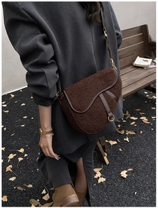 Detail of dark brown teddy plush saddle bag with leather straps and gold buckle