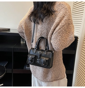 Detail of black pebbled leather crossbody bag with multiple front pockets and silver buckles