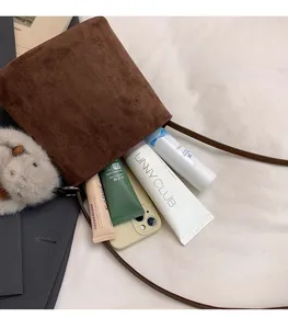 Dettaglio interno della borsa marrone in pelle opaca con oggetti e ciondolo di peluche