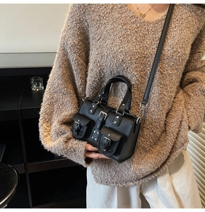 Detail of black lychee leather handbag featuring silver metal buckles and double pockets