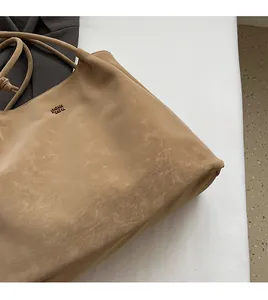 Dettaglio della morbida pelle PU kaki e del logo metallico sulla borsa tote grande