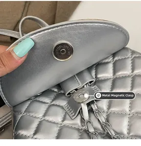 Detail of silver quilted backpack showing metal magnetic buckle closure and chain strap