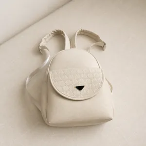 Detail of white lychee leather backpack showing quilted flap and triangle metal buckle