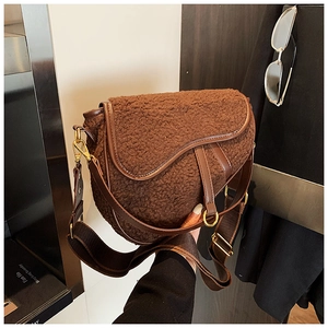 Detail of dark brown teddy faux fur saddle bag with leather accents and metal buckle