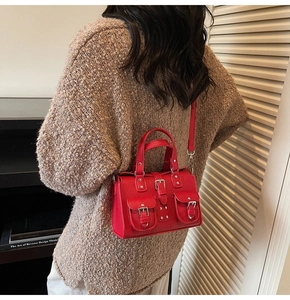Detail of red lychee leather handbag with dual front pockets worn on shoulder