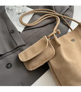 Dettaglio della borsa a spalla beige minimalista con ciondolo a busta e logo in metallo