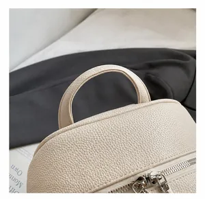 Detail of off-white lychee leather handle and metallic silver double zippers on backpack