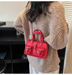 Detail of red lychee pattern leather handbag with silver studs and pocket accents