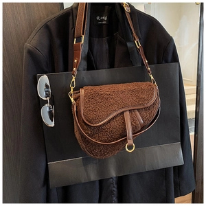 Close-up of brown faux fur saddle bag with vintage leather straps and gold metal hardware