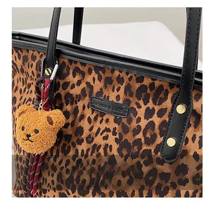 Detail der Tragetasche mit Leopardenmuster, schwarzem PU-Griff und Teddy-Anhänger