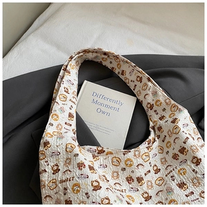 Detail of white quilted tote bag featuring cute cartoon bear prints and textured fabric